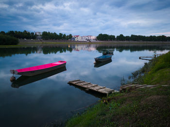 Boat moored on lake against sky