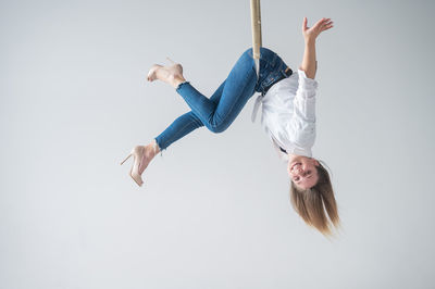 Full length of young woman exercising against white background