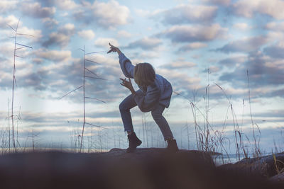 Side view of woman standing on land against sky