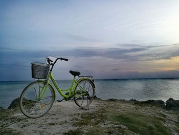 Bicycle by sea against sky