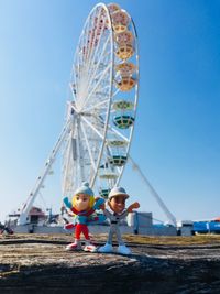 Ferris wheel in amusement park against clear blue sky