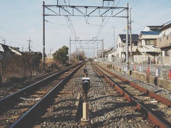 Railway signal amidst railroad tracks against sky