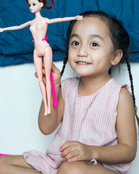 Cute girl playing with doll at home