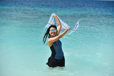 Portrait of young woman standing in sea against sky