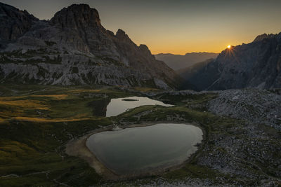 Scenic view of lake by mountains against sky during sunset