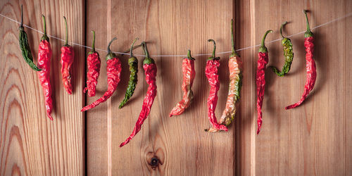 Dried chili peppers hanging by wooden plank