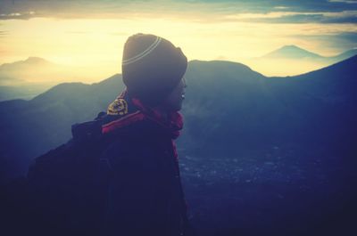 Man standing on mountain against sky during sunset