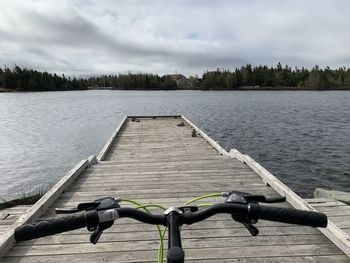 Deck chairs by lake against sky