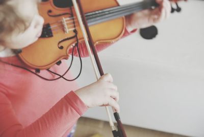 High angle view of girl playing violin by wall at home