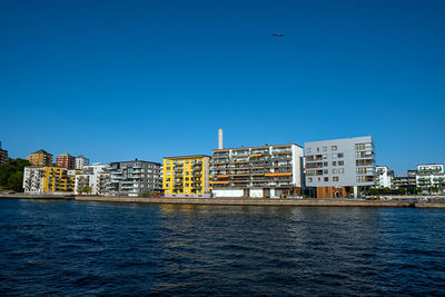 River by buildings against clear blue sky