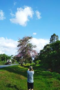 Rear view of man standing by road against sky