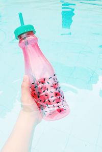 Cropped hand holding bottle in swimming pool