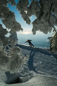 High angle view of man snowboarding standing against sea during winter