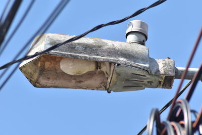 Low angle view of telephone pole against clear blue sky