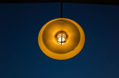 Low angle view of illuminated lantern against blue sky