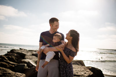 Parents standing on jetty holding infant son