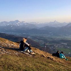 People sitting on mountain against sky