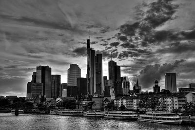 City at waterfront against cloudy sky