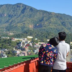 Rear view of people looking at mountain against sky