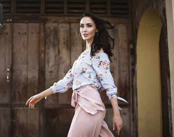 Portrait of woman standing against wall