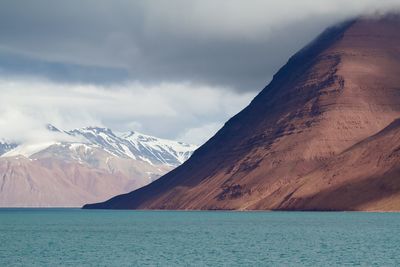 Arctic mountains and screes fall towards a turquoise sea