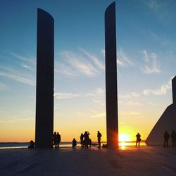 Silhouette people against sea against sky during sunset