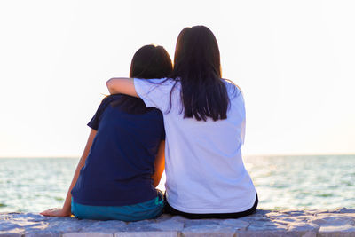 Rear view of friends looking at sea against sky