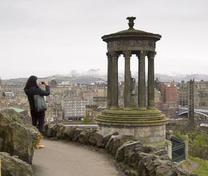 Side view of woman photographing historical building