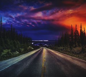 Road amidst illuminated trees against sky at night