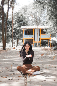 Portrait of woman sitting on snow covered tree