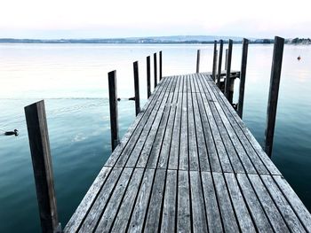 Wooden pier in sea against sky