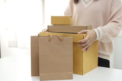 Midsection of woman holding box against white background