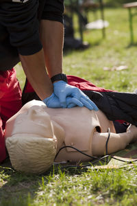 Midsection of woman learning cpr on grassy field