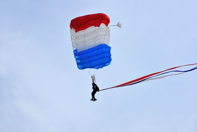 Low angle view of person paragliding against blue sky