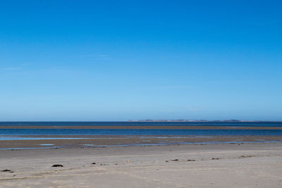 Scenic view of beach against blue sky