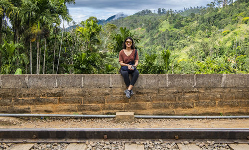 Woman sitting on stonewall at famous railroad bridge in ella