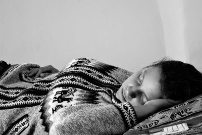 Woman sleeping on bed against wall at home
