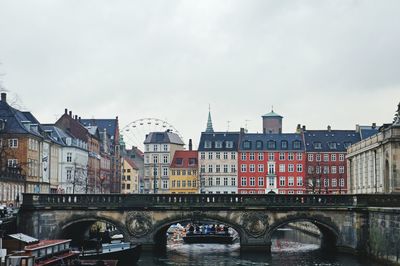 Bridge over river in city against sky