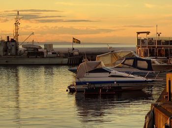 Boats moored at harbor during sunset