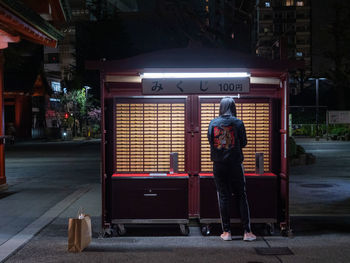 Rear view of man walking on street at night