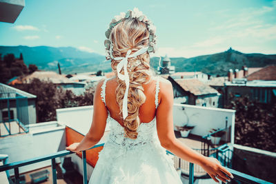Midsection of woman standing by swimming pool against sky