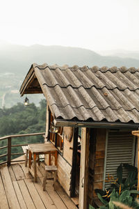 Wooden table and houses on mountain against sky