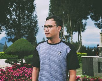 Portrait of young man standing by plants