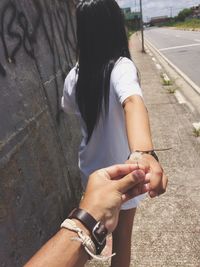 Cropped hand of man holding dandelion flower and woman on sidewalk