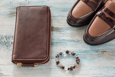 High angle view of clutch bag and bracelet with shoes on table