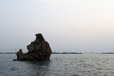 Rock formation in sea against clear sky