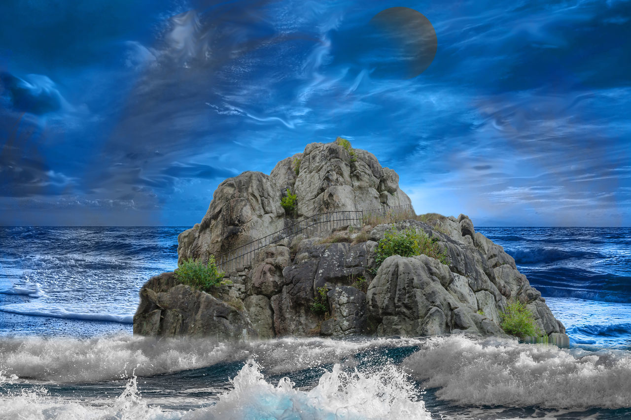 ROCK FORMATION ON BEACH AGAINST SKY