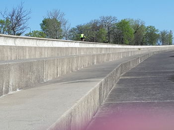 Footpath by retaining wall against clear sky