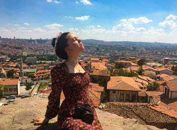 Woman looking at city buildings against sky