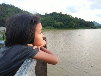 Girl looking at lake against mountains